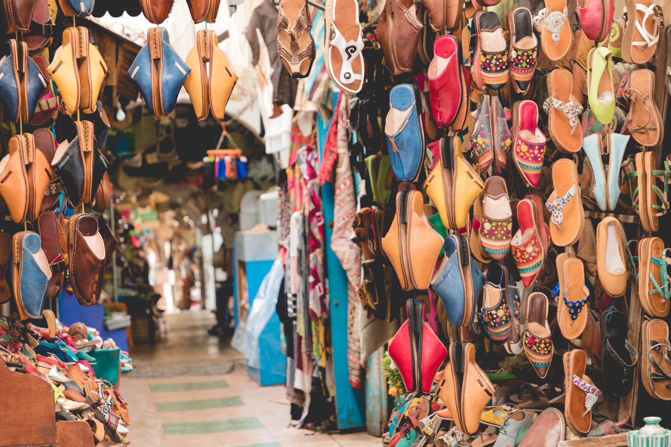 Colorful leather shoes and sandals hanging for sale in the old medina, with many different styles in blue, red, yellow, and brown colors